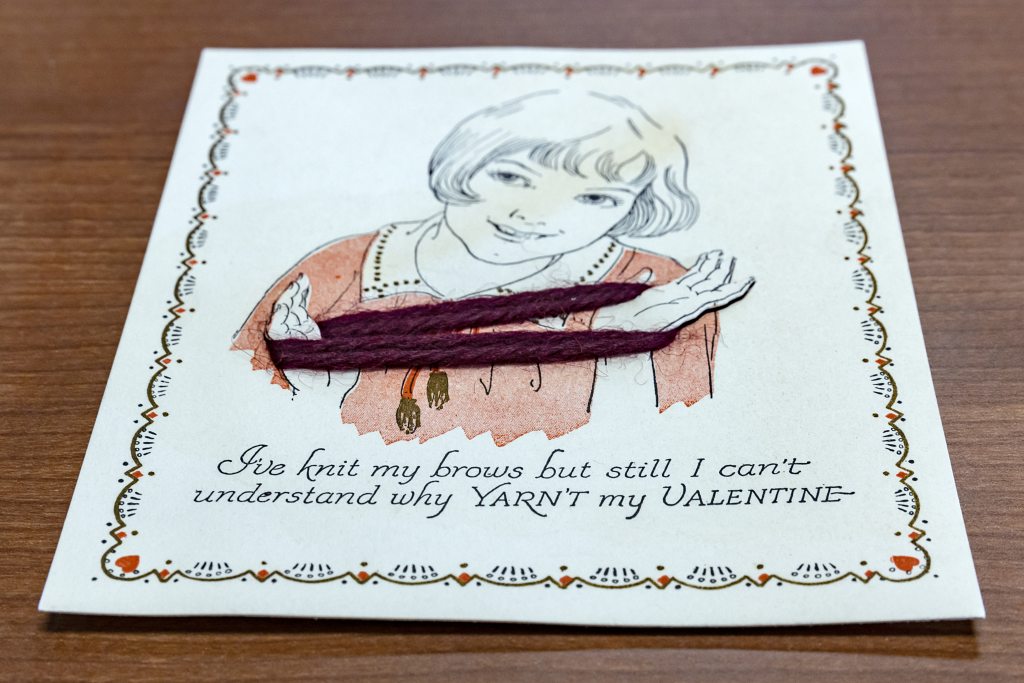 A card that depicts a young woman holding a piece of yarn
