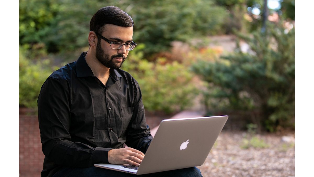 Nihar Vaidya sitting outside using his laptop.