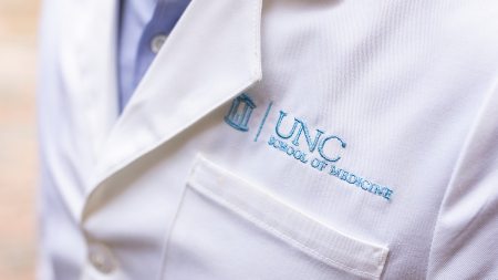 A white doctor coat with UNC School of Medicine on it.
