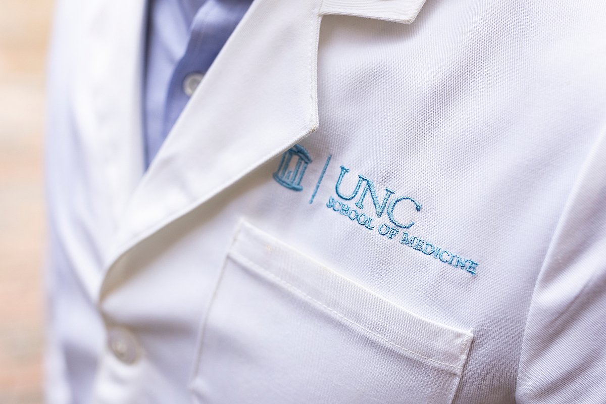 A white doctor coat with UNC School of Medicine on it.