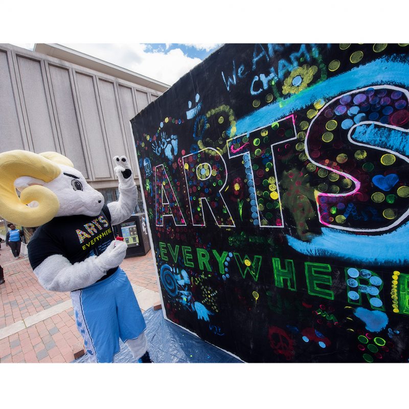 A ram mascot next to a mural painted 