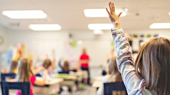 A student raising their hand in a classroom.