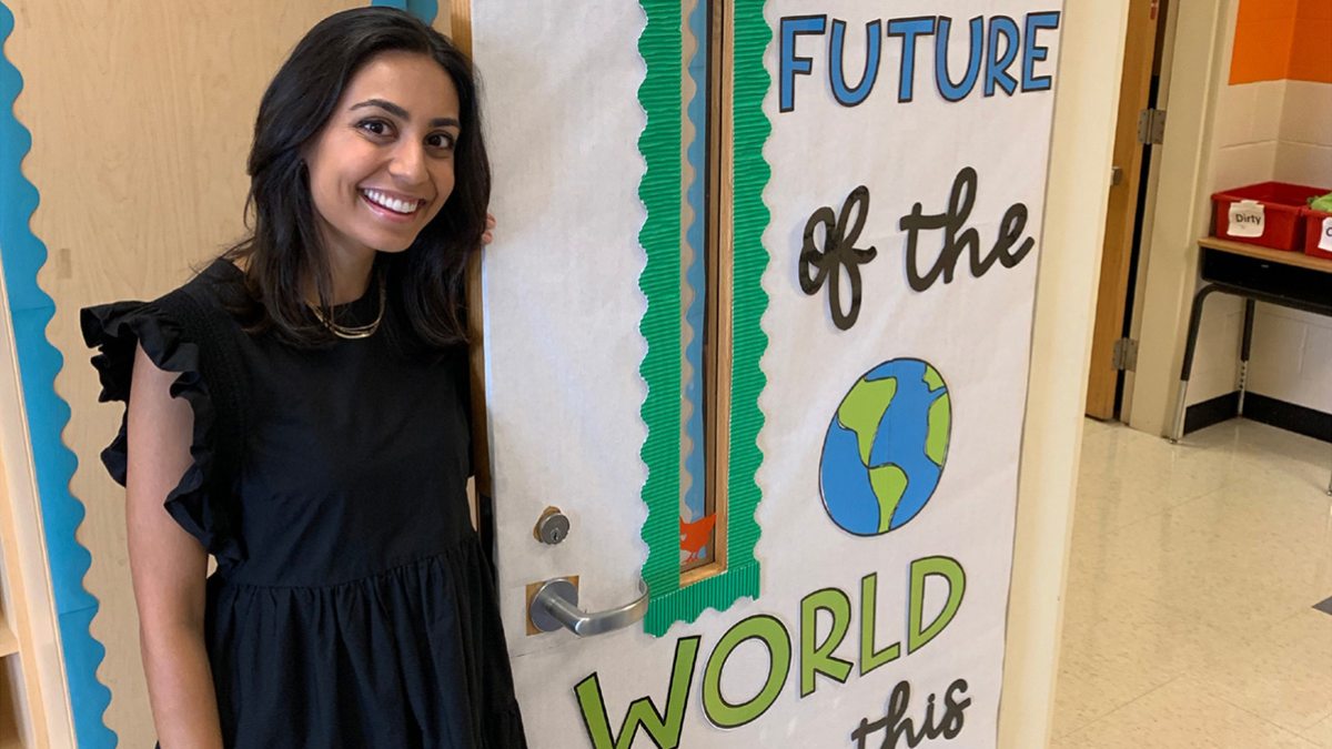 Asha Patel standing by her classroom door.