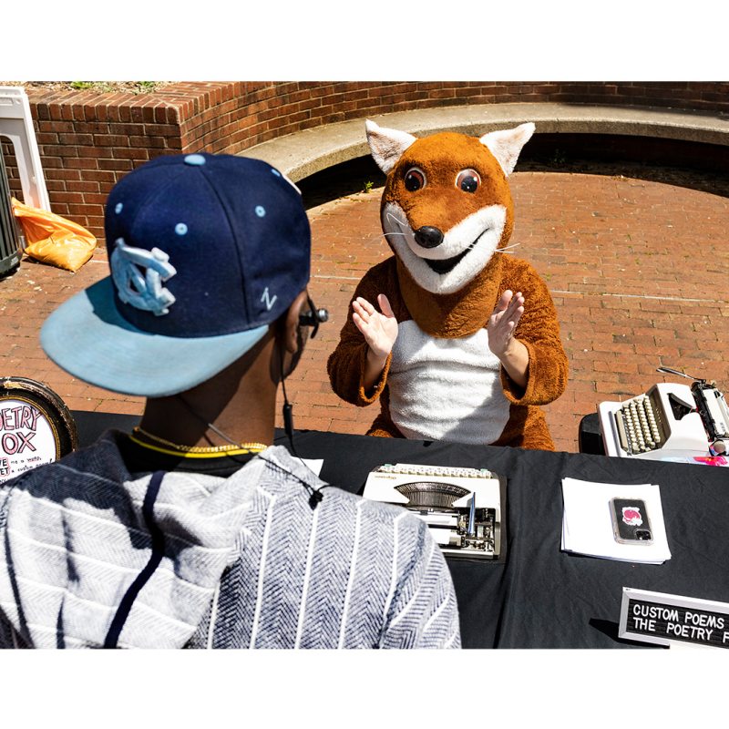 A person talks to a person dressed in a fox costume.