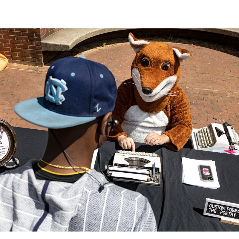 A person dressed up like a fox using a typewriter.