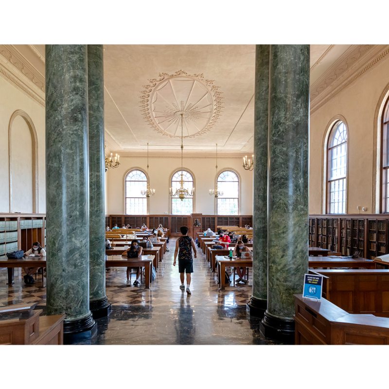 A student walking in Fearrington Reading Room in Wilson Library.