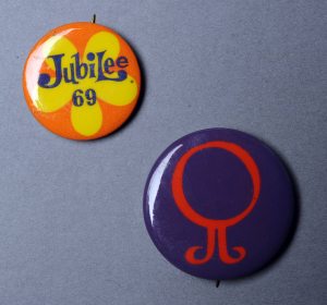 Two buttons, one navy with a red swirl and the other orange and yellow with "Jubilee 1969" printed on it