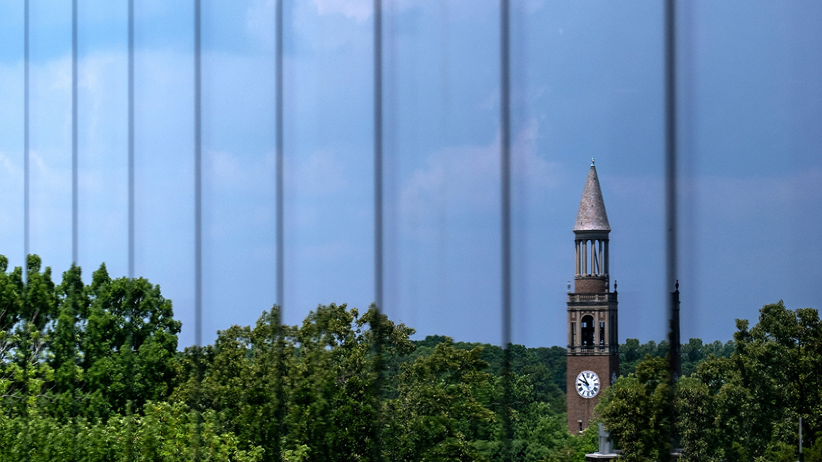 The bell tower is reflected on glass.