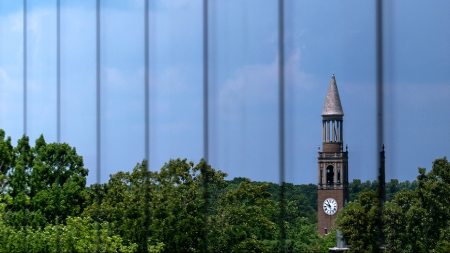 The bell tower is reflected on glass.