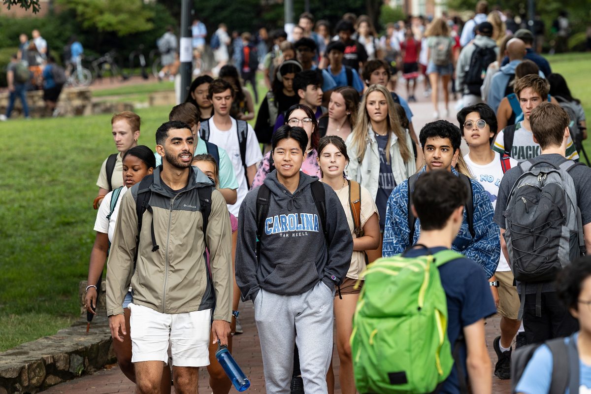 A large group of students walk on campus