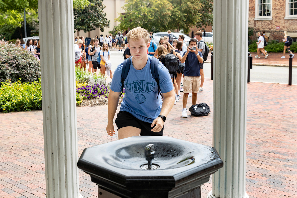 A student walks toward the Old Well