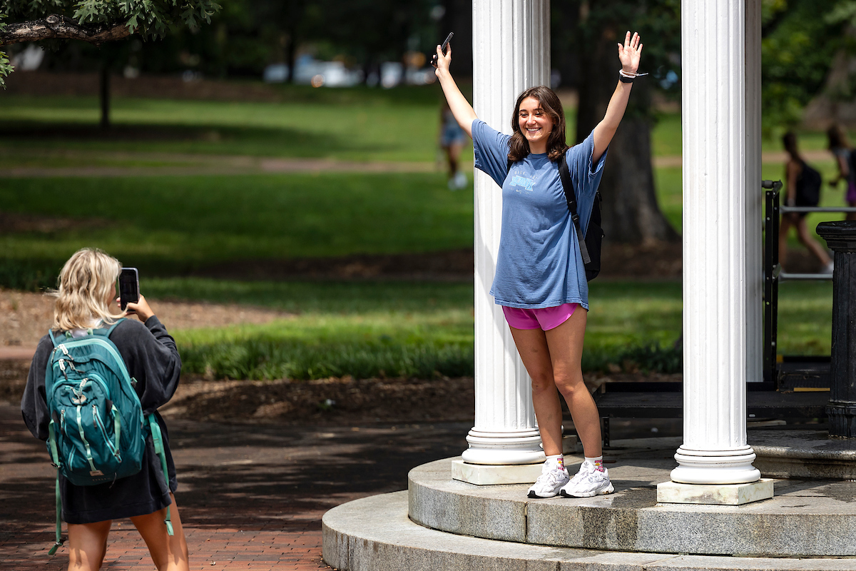 A student poses with her hands above her head at the Old Well