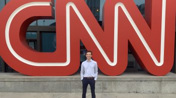 Preston Fore standing in front of the CNN logo.