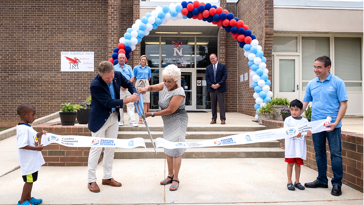 Chancellor Kevin M. Guskiewicz and Person County Schools Board of Education Chair Freda Tillman cut the ribbon held by UNC School of Education Dean Fouad Abd-El-Khalick and North Elementary School students Liam Adam and Adrian Gomez-Patricio.