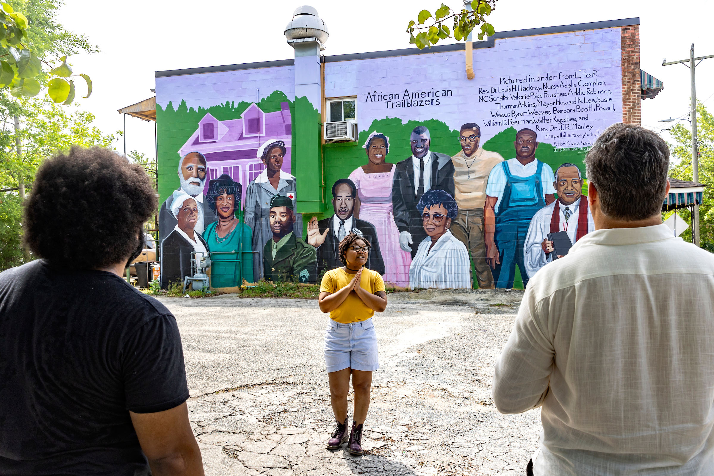 A person standing in front a mural of African American trailblazers.