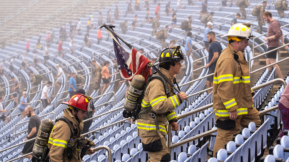 A firefighter with a flag climbs stairs.