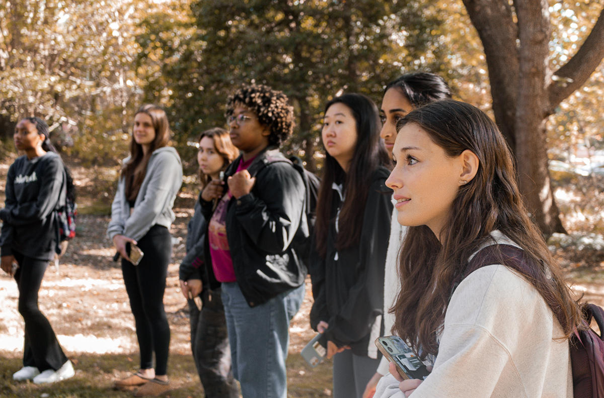 Students listen during a class outside in a garden.
