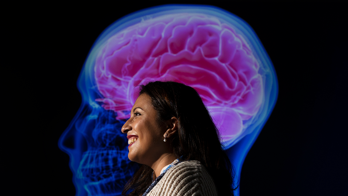 A woman standing in front of an image of a brain.
