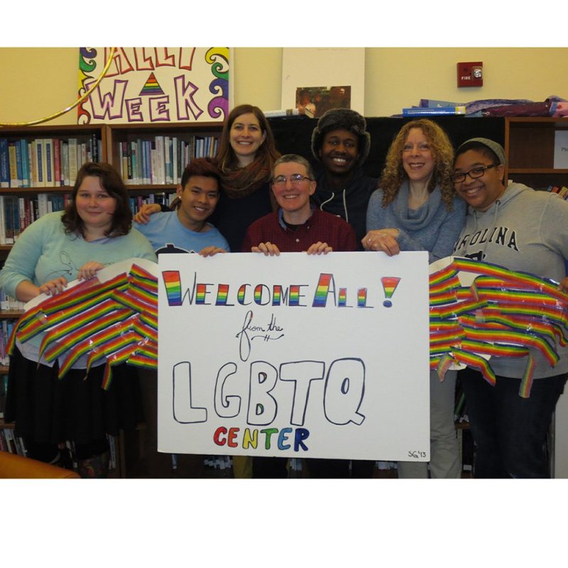 Students hold a said about the LGBTQ Center.