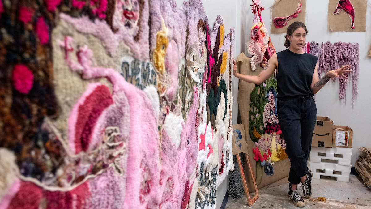 A person standing next to fabric art.