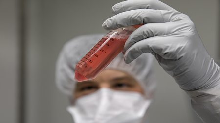 A researcher holds a tube of patient cells.