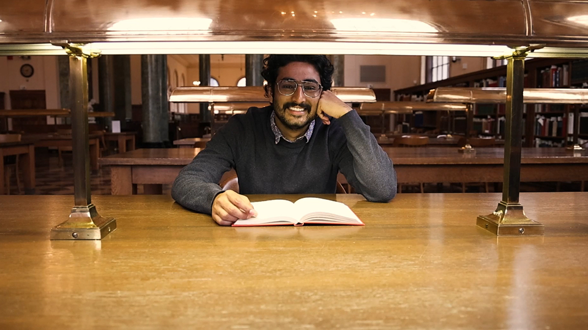 Tushar Varma sitting at a desk with a book.