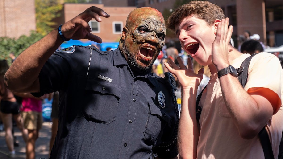 A person next to a cop with zombie makeup on.