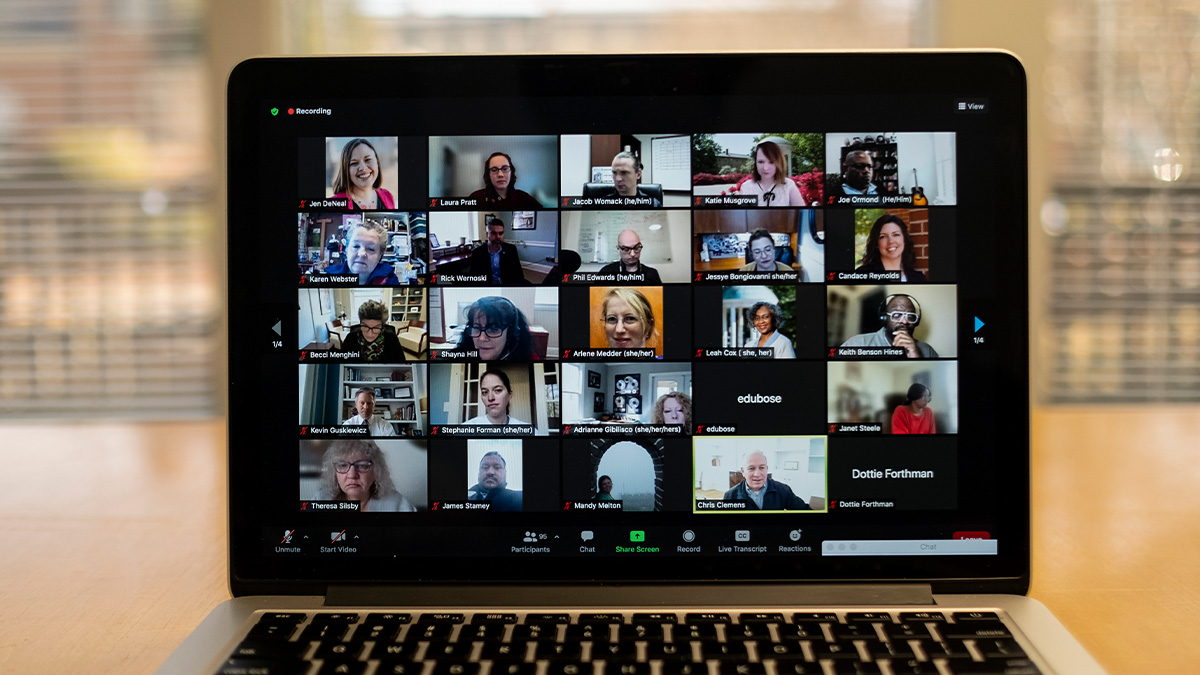 Notebook screen with thumbnails of 25 participants meeting on Zoom.