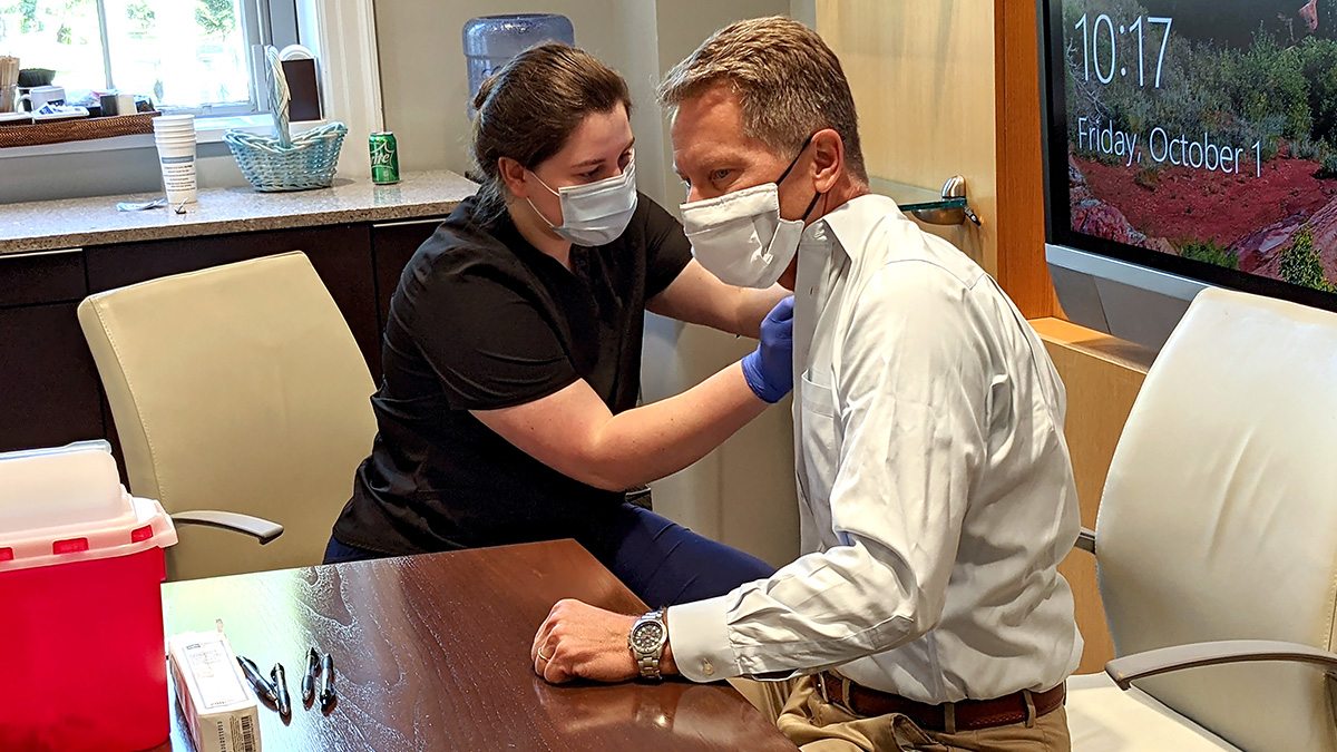 Nurse giving Kevin Guskiewica a flu shot