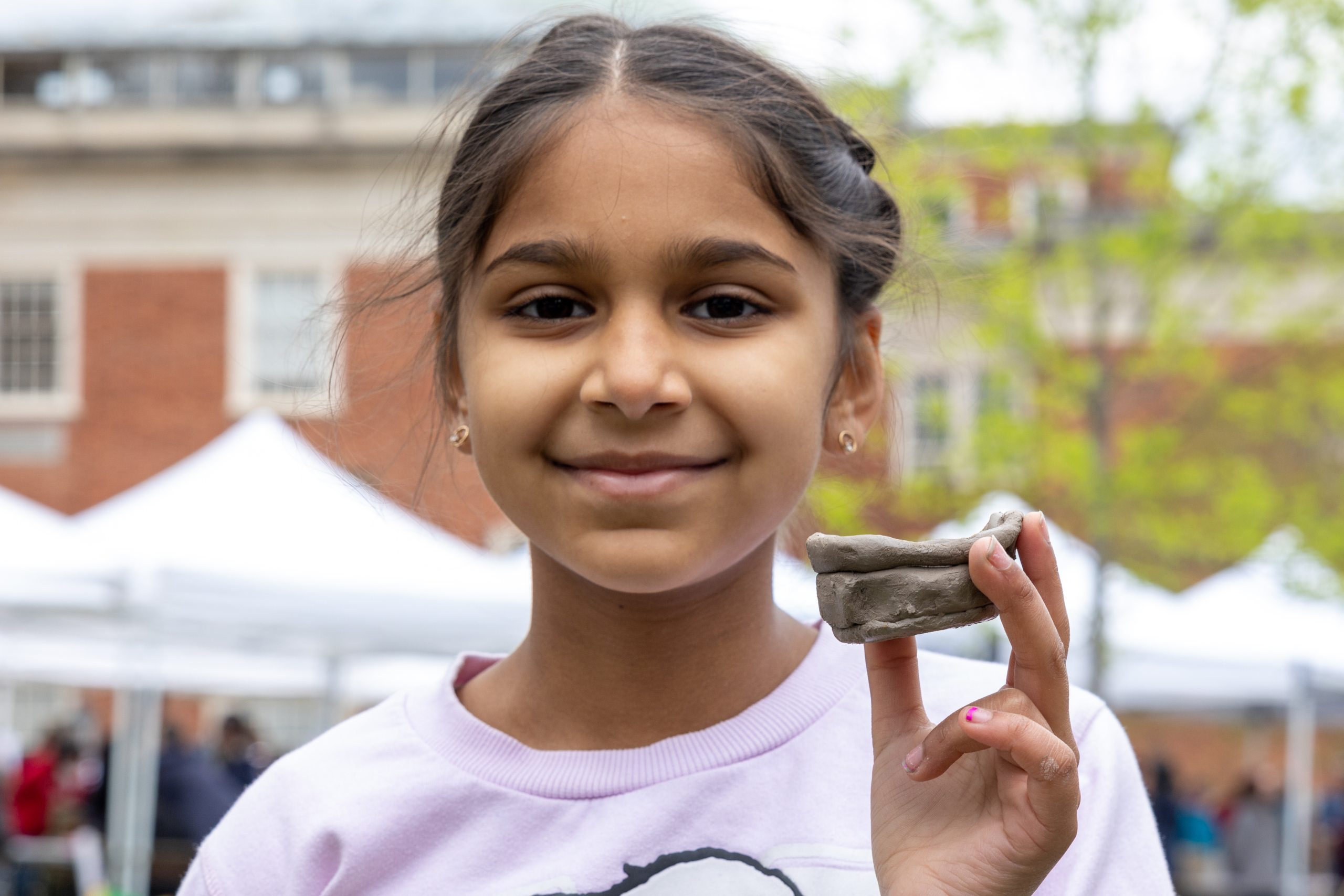 Young participant holds a hand-made clay pinch pot.