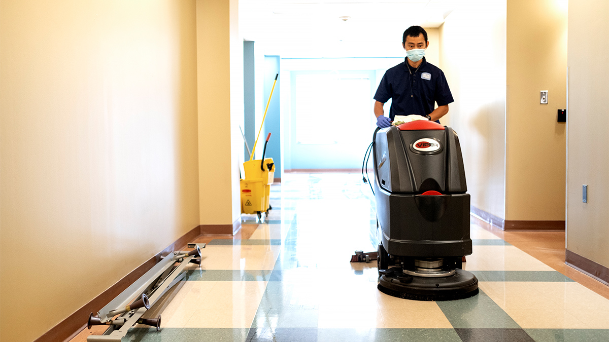 UNC Housekeeping Crew Leader Has Ka Nyaw uses a large machine to polish a hallway in Taylor Hall.
