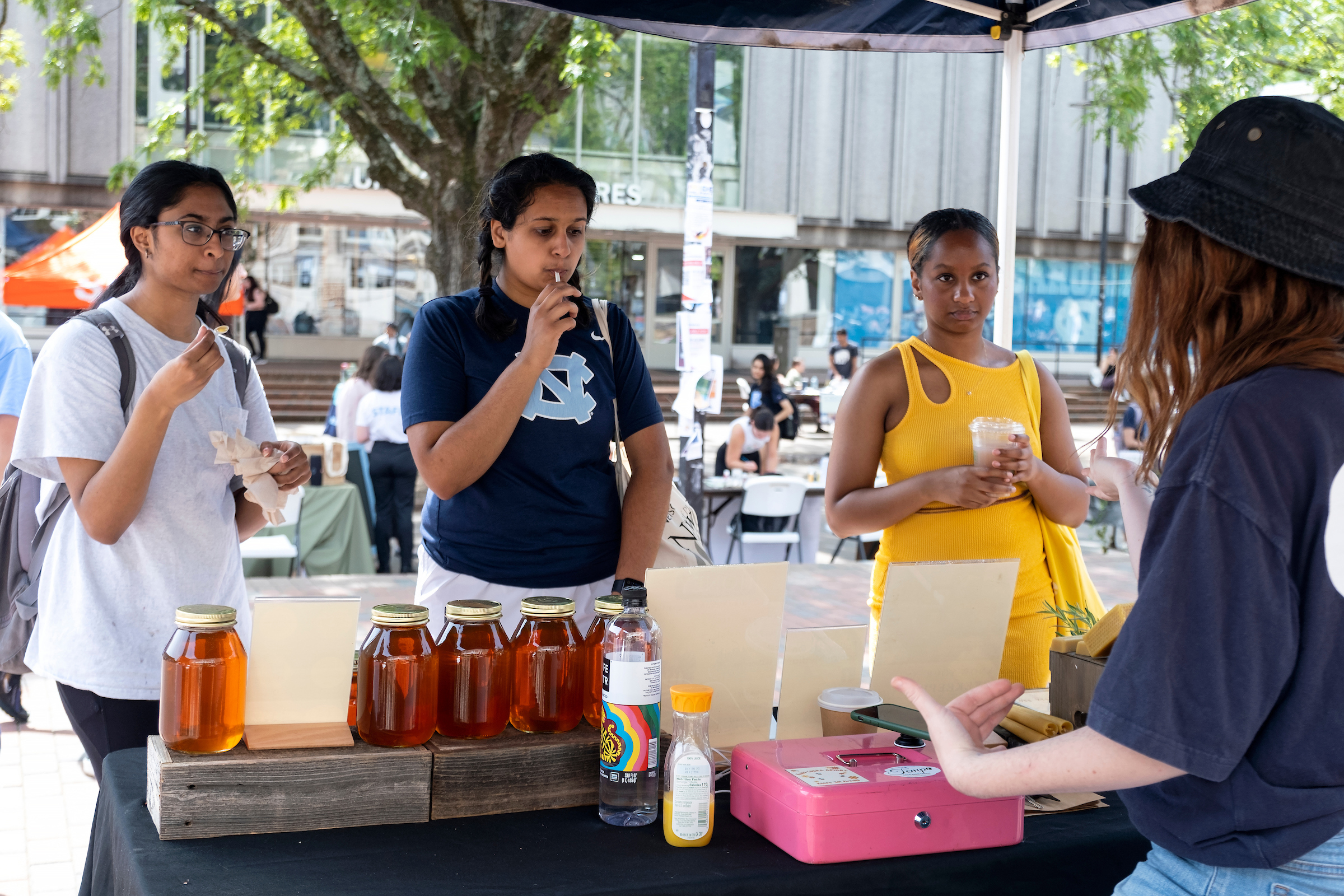 Students sample honey from King Cobra Apiary during a farmers market in the Pit. (Jon Gardiner/UNC-Chapel Hill)