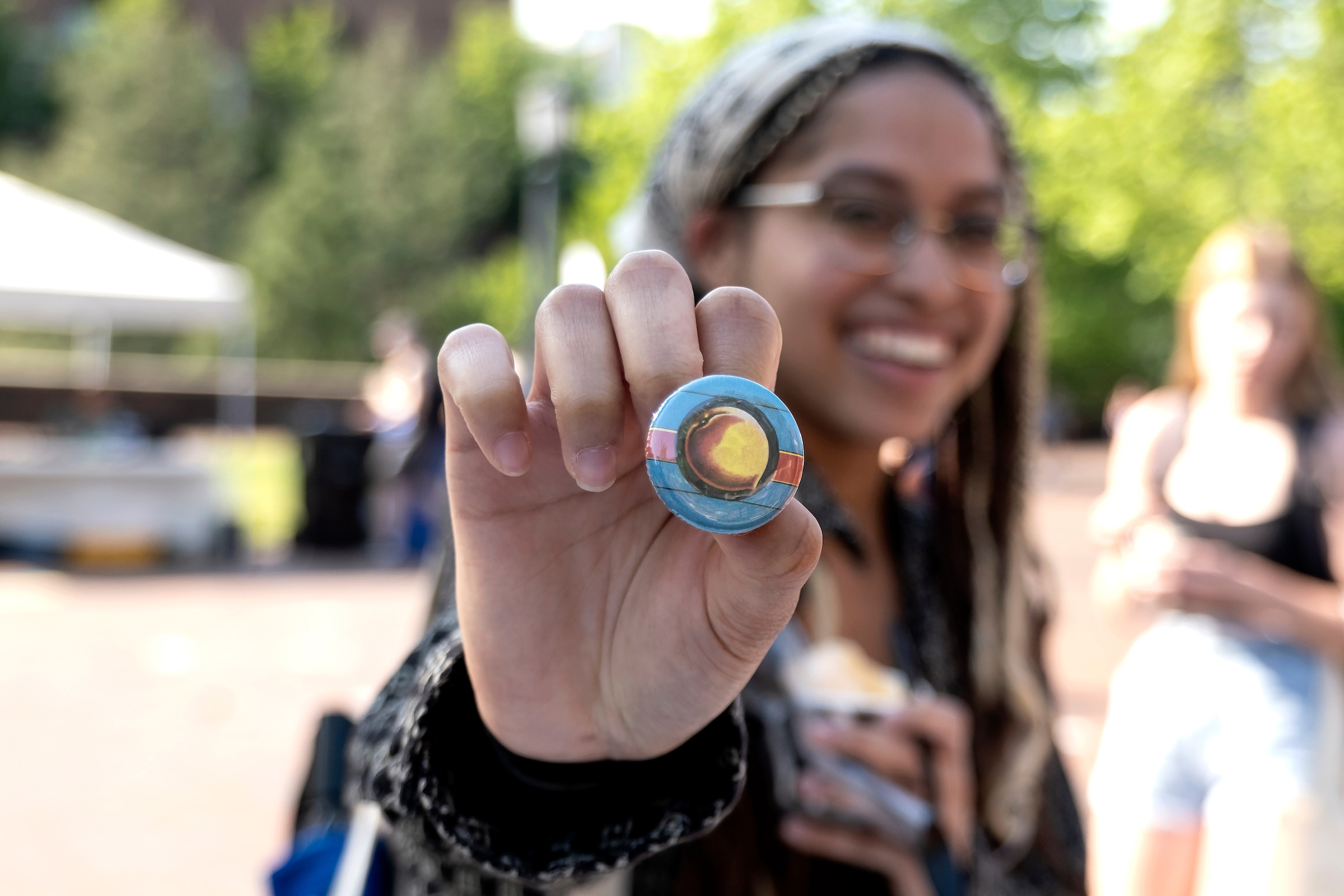 A student holds out a button with an image of a peach on it toward the camera. Making buttons from images provided by University Libraries was part of an Earth Day festival hosted by Sustainable Carolina. (Jon Gardiner/UNC-Chapel Hill)
