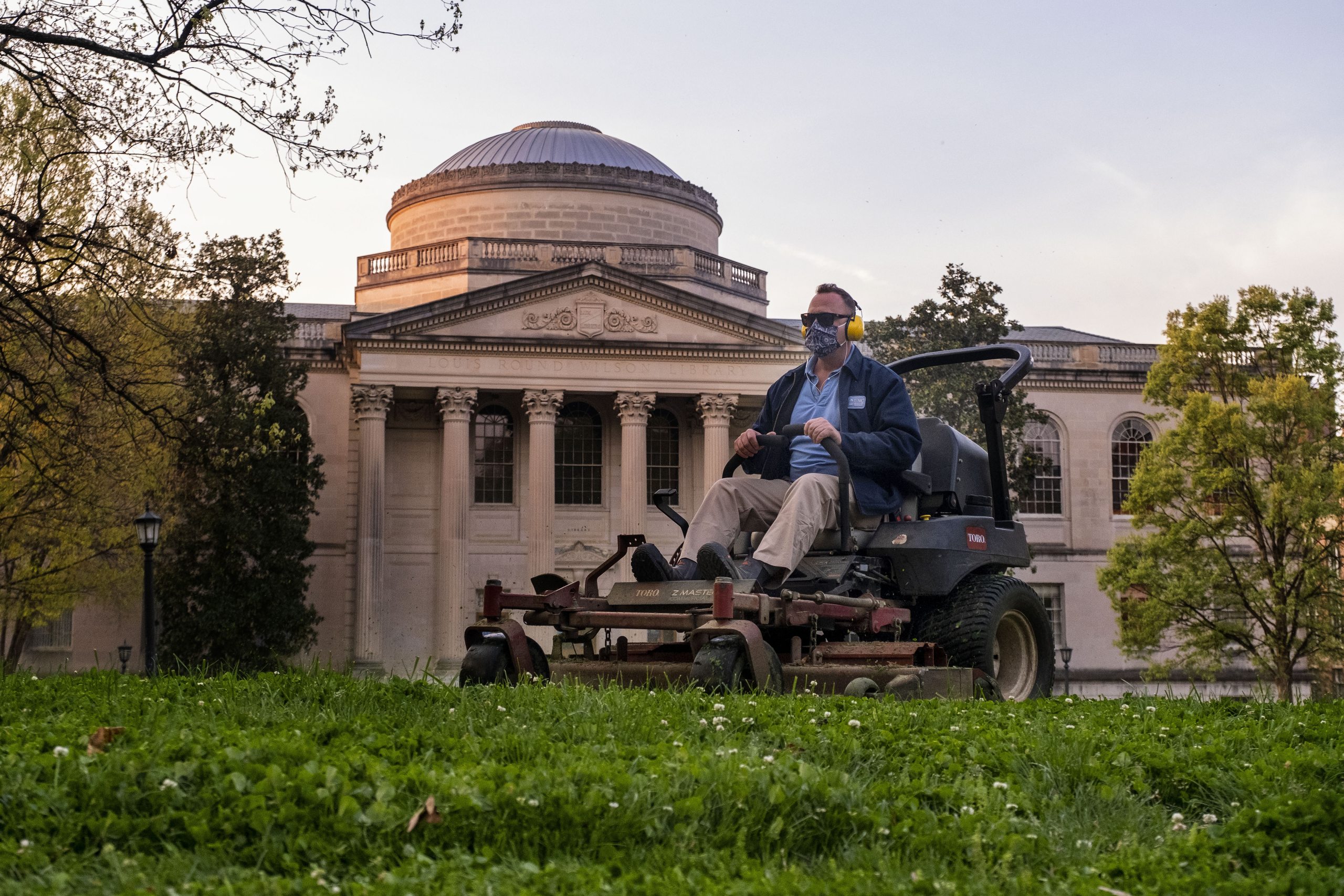 Eric Tolar cuts grass on Polk Place in front of Wilson Library. When few people were on campus from March into summer, Tolar and his crewmates took care of 81 acres of the University’s most visible outdoor areas. “The number one thing we’ve been about is being safe,” Tolar said. “I’ve felt fortunate to be at work at times when the news is 24-7 and can bring you down. We were outside and able to take our minds off of it. And, we could see that people were here at times.”