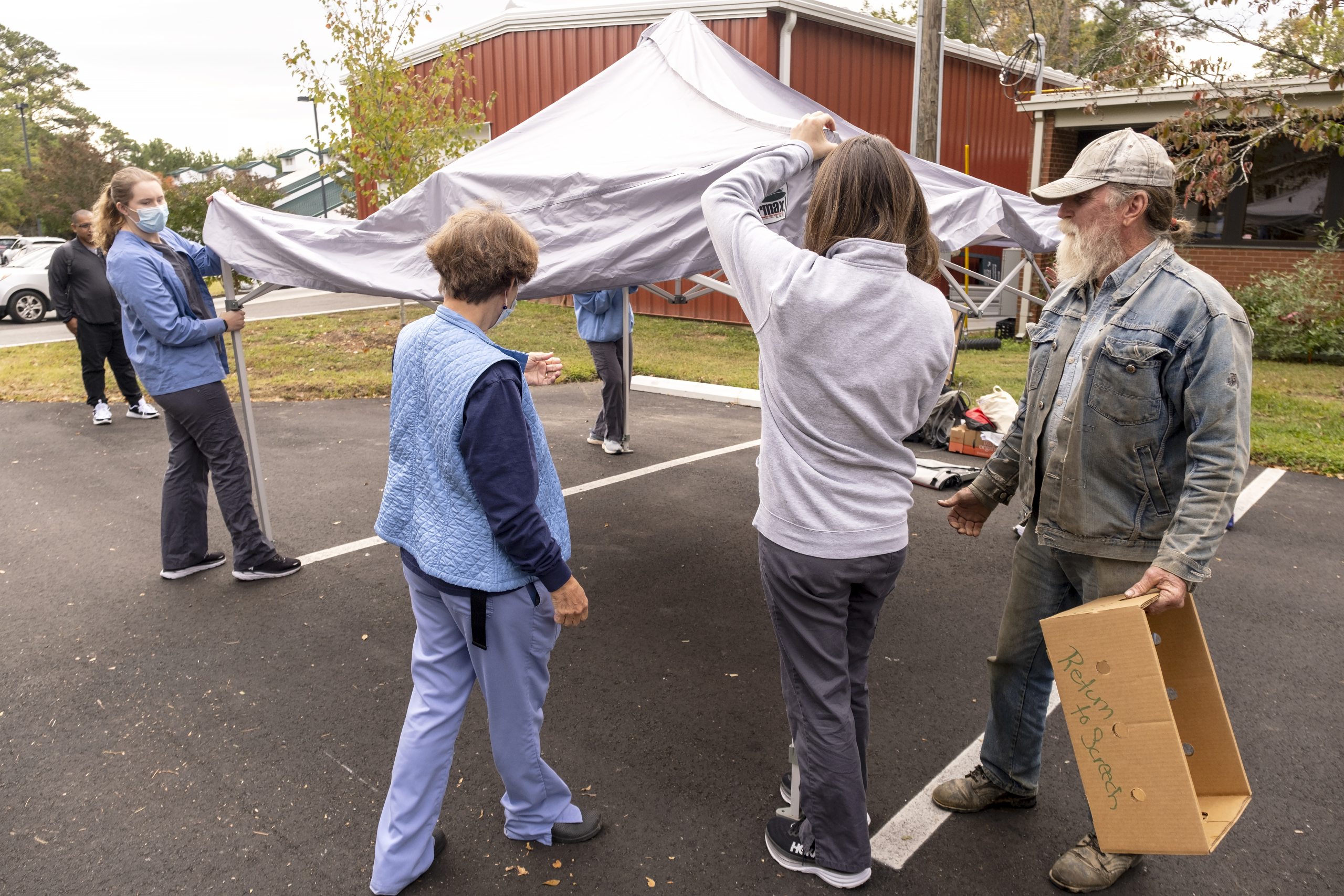 With help from a local farmer, four nursing students and Associate Professor Jean Davison are put up a tent under which students can perform health assessments that might indicate a health problem such depression or diabetes.