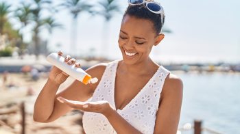 A woman at a beach applying sunscreen.