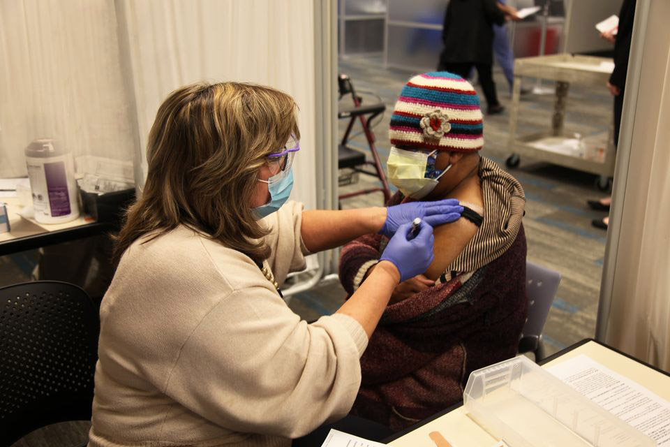 A woman receives a COVID-19 vaccination at the UNC Health clinic at the Friday Center.