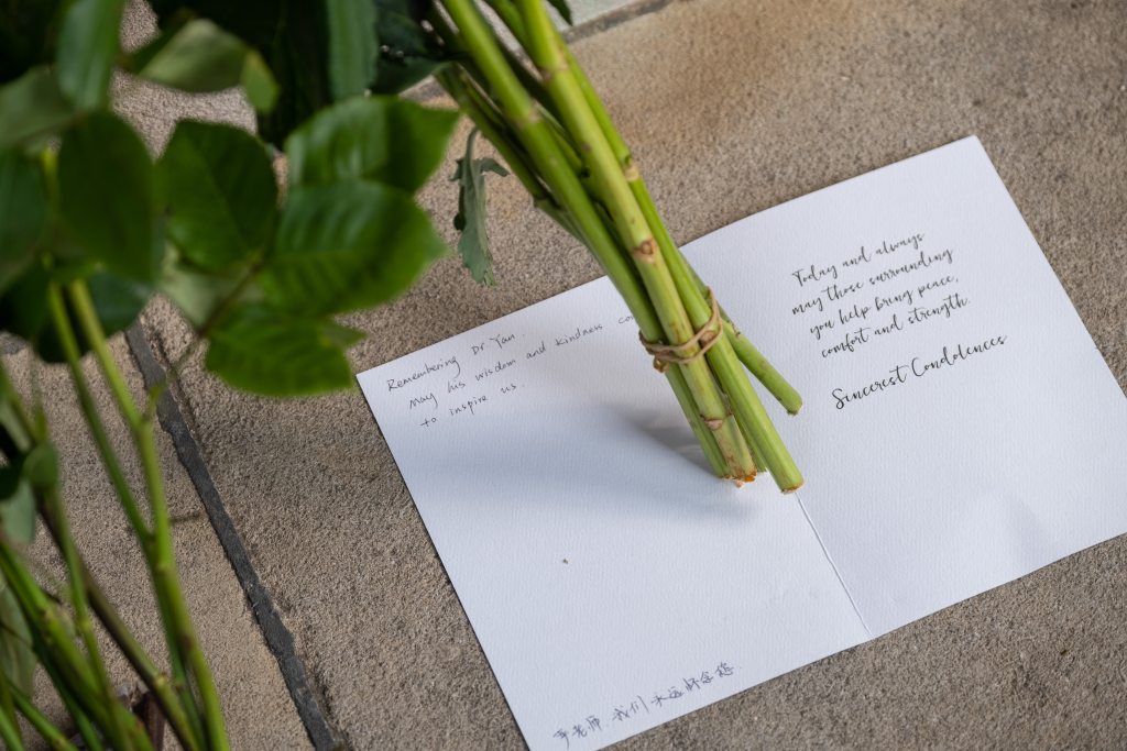 A handwritten letter with a flower placed on top of it.