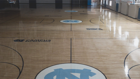 A basketball court with the UNC-Chapel Hill athletics logo at halfcourt and reading 