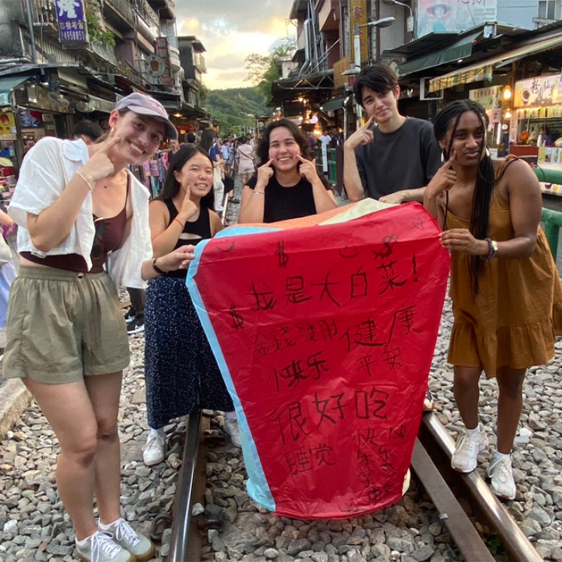 Five students holding up a red banner with Chinese text.