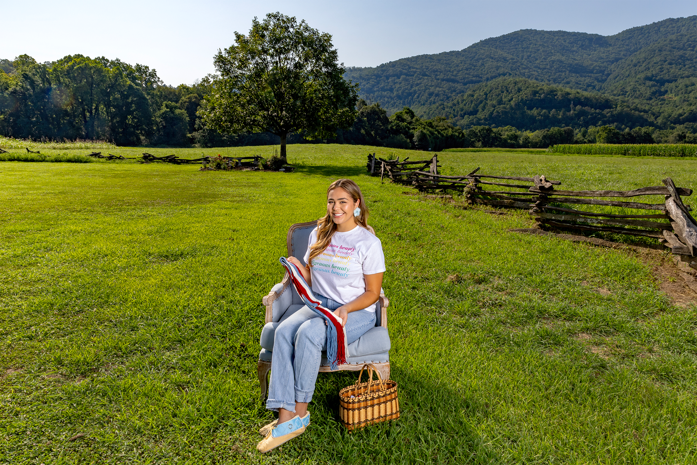 A woman named Tsini McCoy sitting in a blue chair and posing for a portrait in a field on a sacred Cherokee site.