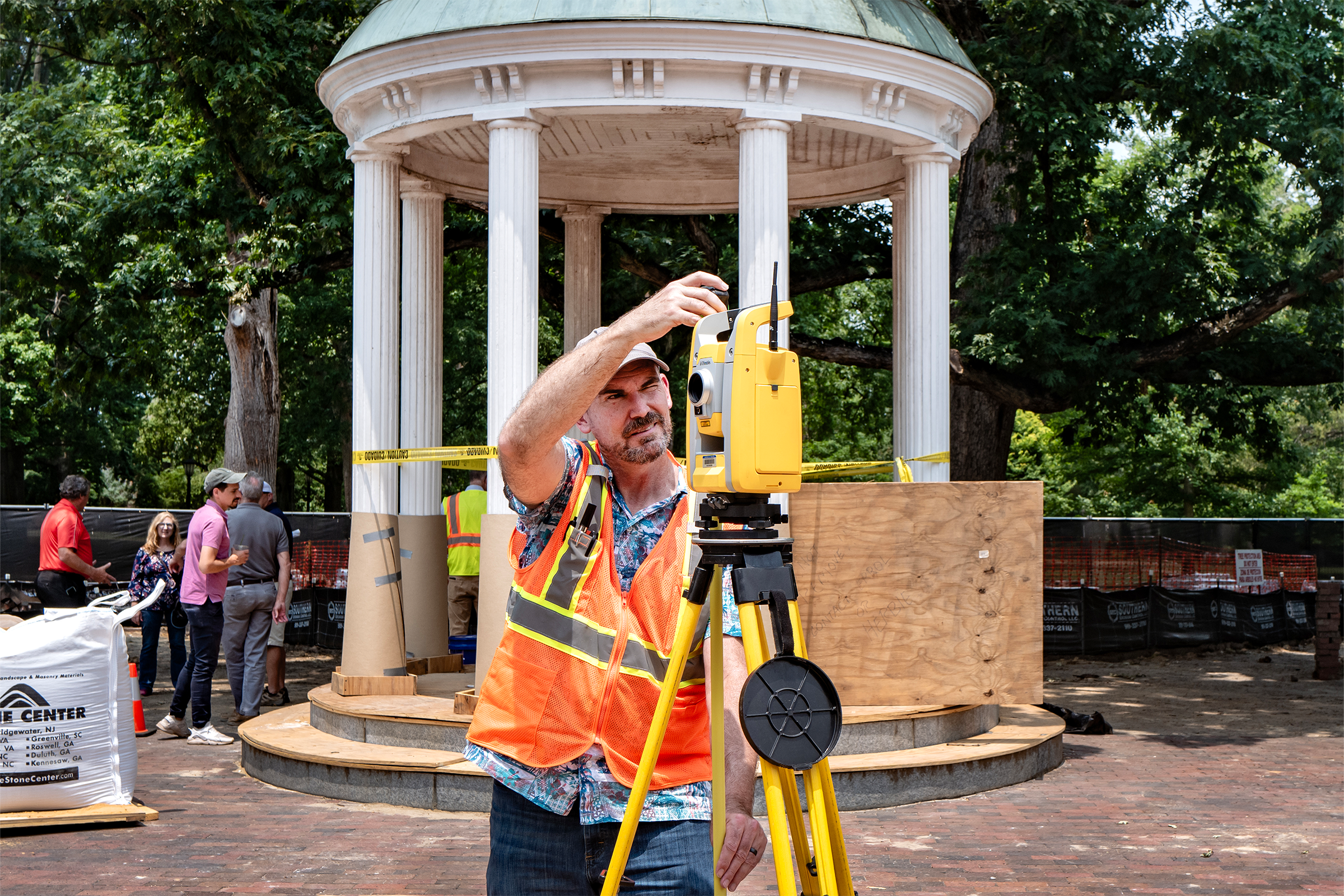 A worker using surveying equipment next to a well.