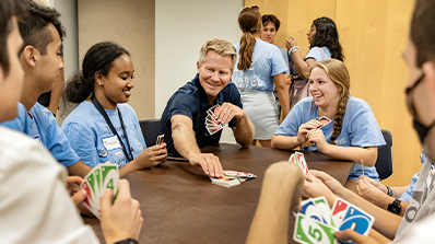 A group of first-year UNC-Chapel Hill students playing cards at a table with Chancellor Kevin M. Guskiewicz