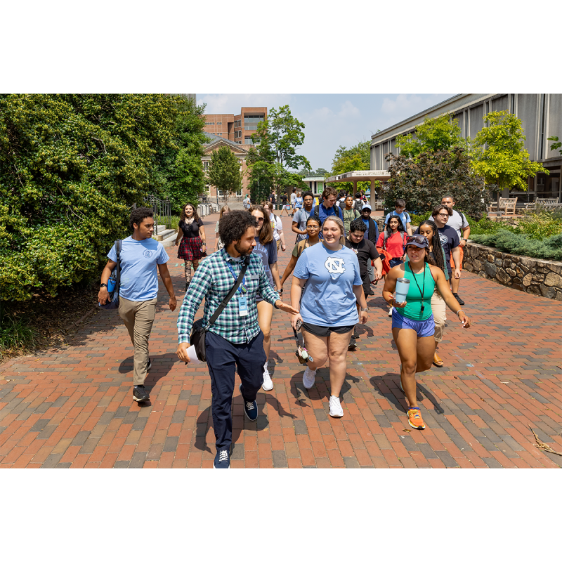 A group of students walking on a brick pathway around the campus of UNC-Chapel Hill.