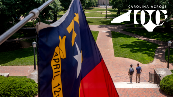 Campus scene with flag and Carolina Across 100 logo