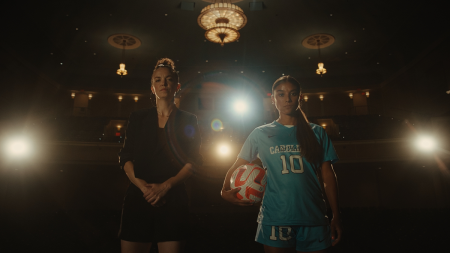 A dancer and a soccer player holding a ball posing for a photo next to each other in a theater.