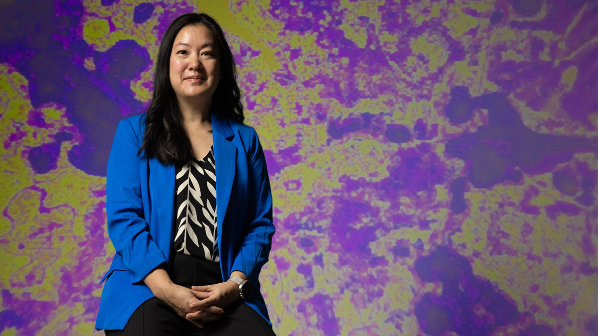 Professor Angel Hsu poses in front of purple and yellow heat map.