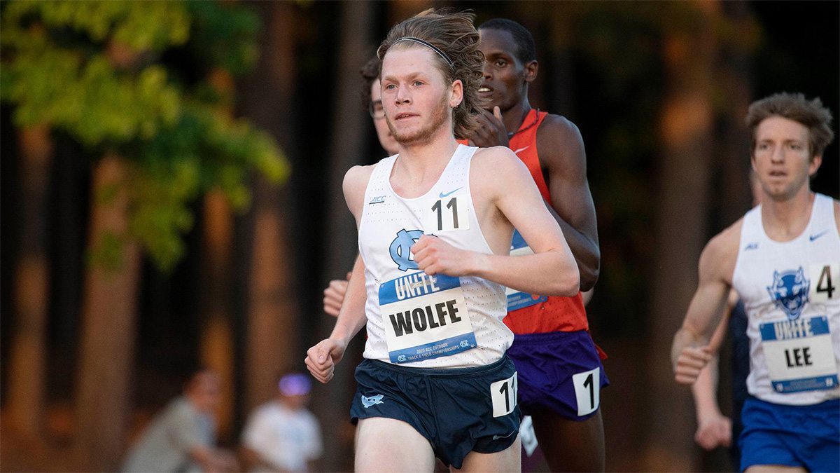 Cross country runner, Parker Wolfe, runs ahead of competition close behind him with a name tag reading 