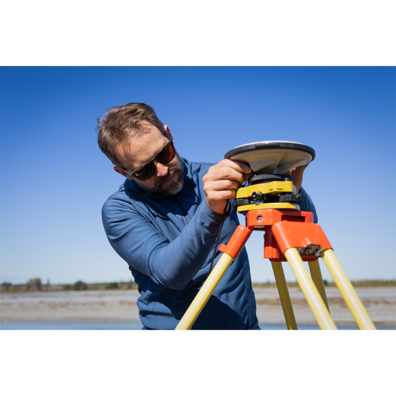 A researcher configuring a measurement tool near a river.