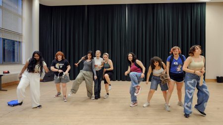 Nine students in a rehearsal studio, practicing choreography.